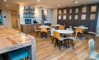 a modern restaurant with wooden floors , white walls , and multiple tables and chairs arranged in an open space at Residence Inn Upper Marlboro Joint Base Andrews
