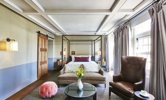 a modern bedroom with a bed , chair , and ottoman , as well as a vase of flowers on the floor at The Hollywood Roosevelt