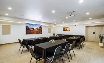a conference room with black tables and chairs , a large painting on the wall , and recessed lighting at Red Sands Hotel