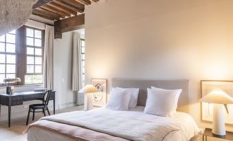 a large bed with white linens and a wooden headboard is in a room with exposed beams at Les Manoirs des Portes de Deauville - Small Luxury Hotel of the World