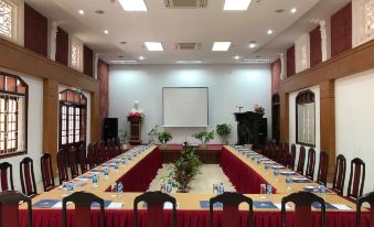 a large conference room set up for a meeting , with multiple chairs arranged in rows and a projector screen on the wall at Saigon-Ba Be Resort