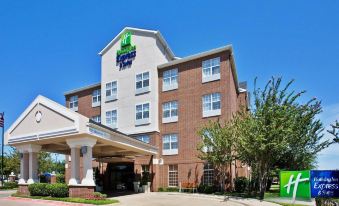 a holiday inn express hotel with its logo , surrounded by trees and clear skies at Holiday Inn & Suites Dallas-Addison