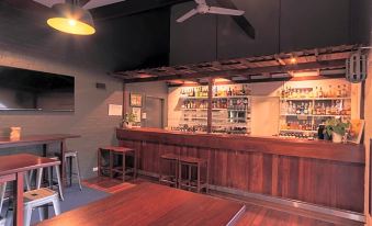 a bar with a wooden counter and stools , as well as a large selection of liquor bottles on the shelves at Manjimup Kingsley Motel