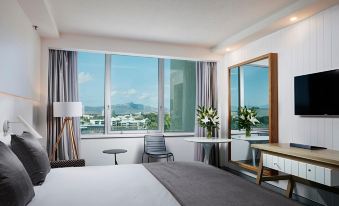 a modern hotel room with a large window offering a view of the city , a bed , and a table at The Ville Resort - Casino