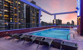 There is a swimming pool on the roof, with an apartment in front and another building behind it at Ramada Hong Kong Harbour View