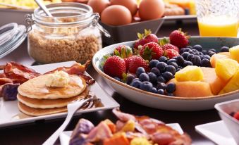 a dining table with a variety of breakfast foods , including pancakes , fruit , and other dishes at Hyatt Place Melbourne / Palm Bay / I-95