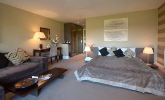 a spacious bedroom with a king - sized bed , a flat - screen tv , and a dining table in the background at Thornton Hall Hotel & Spa