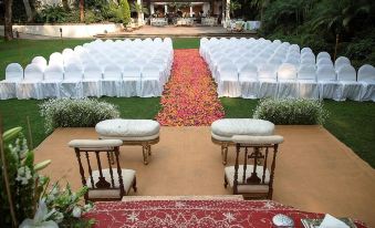 a large outdoor wedding ceremony is taking place in a courtyard , with rows of white chairs and tablecloths set up for guests at Las Mananitas Hotel Garden Restaurant and Spa