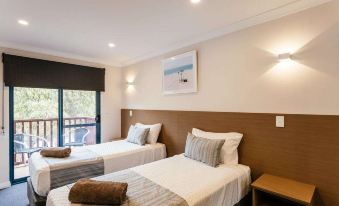 a hotel room with two beds , one on the left side of the room and the other on the right side at Dolphin Lodge Albany - Self Contained Apartments at Middleton Beach