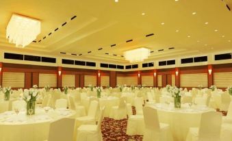 a large banquet hall with numerous tables and chairs arranged for a formal event , possibly a wedding reception at Grand Asrilia Hotel