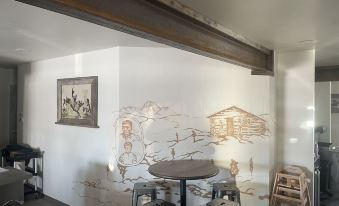 a room with a table and stools , featuring a mural of a house on the wall at Challis Roadhouse