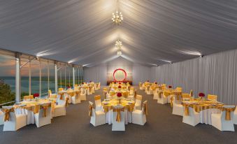 a large white tent with multiple dining tables set up for a formal event , possibly a wedding reception at DoubleTree by Hilton Goa - Panaji