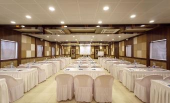 a large conference room with rows of chairs and tables , all covered in white tablecloths at Serena Beach Resort