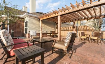 a patio area with a wooden pergola , several chairs , and a dining table set up for outdoor dining at Homewood Suites by Hilton Columbus - Hilliard