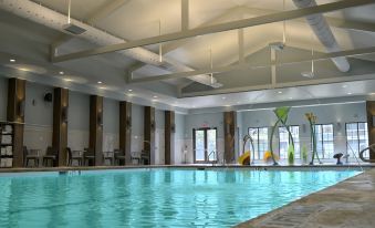 an indoor swimming pool with a large glass window , surrounded by lounge chairs and tables at Hilton Myrtle Beach Resort