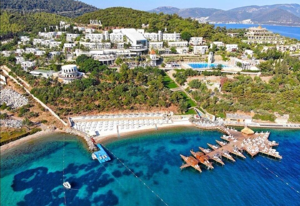 aerial view of a beautiful beach resort with white buildings , clear blue water , and tropical vegetation at Duja Bodrum