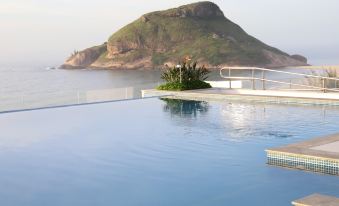 a large outdoor swimming pool surrounded by lush greenery , with a view of a mountain in the background at CDesign Hotel