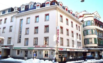 "a large white building with a sign that says "" hotel "" in front of it , surrounded by snow" at Hotel Weisses Kreuz