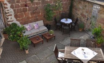 a stone wall and a patio area with several tables and chairs , creating a cozy outdoor space at LUDWIGS