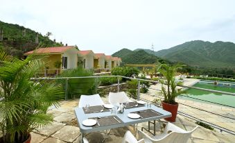 a patio area with a table and chairs set up for a meal , overlooking a pool and mountains at River Rock Resort