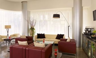 a modern living room with red couches and chairs arranged around a coffee table , creating a cozy atmosphere at Park Plaza Leeds