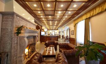 a luxurious living room with wooden ceiling , leather furniture , and a fireplace , under a high ceiling with wooden beams at Festa Winter Palace Hotel