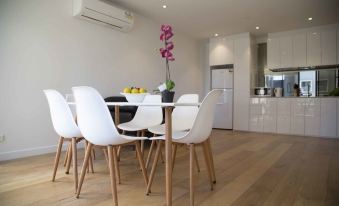 a modern kitchen with white furniture , including a dining table and chairs , in a spacious room at Arrow on Swanston