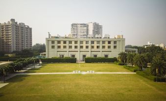 a large building with a green lawn in front of it , surrounded by tall buildings at DoubleTree by Hilton Agra