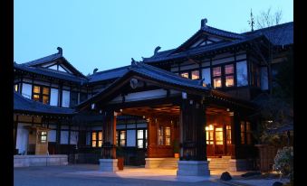 a traditional chinese building with wooden architecture and a large entrance , illuminated at night against the dark sky at Nara Hotel