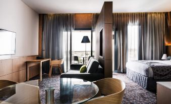 a modern hotel room with a large window , wooden furniture , and a view of the city at Mercure Sydney Liverpool
