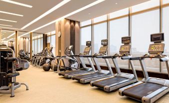 A well-equipped training room with multiple treadmills and large windows is available at Yiwu Marriott Hotel