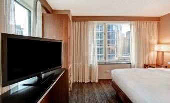 a modern hotel room with a large window , white curtains , and a flat - screen tv on the wall at Embassy Suites by Hilton Chicago Downtown Magnificent Mile