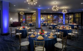 a large banquet hall with multiple round tables set up for a formal event , decorated with blue linens and gold chairs at Hilton Albany