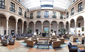 a large , open - air courtyard with multiple chairs and couches arranged around a coffee table in the center at Parador de Lerma