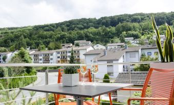 a balcony overlooking a residential area , with a table and chairs set up for outdoor dining at Lumina Apartments