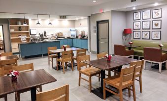 a modern restaurant with wooden tables and chairs , a blue countertop , and a kitchen in the background at Comfort Inn & Suites