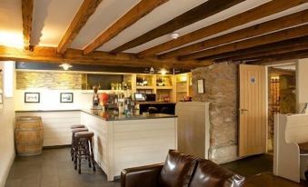 a cozy living room with wooden beams , a couch , and a coffee table , as well as a kitchen area with a bar at The Anchor Inn
