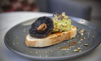 a plate of food on a dining table , consisting of a slice of bread topped with guacamole and an avocado at The White Hart