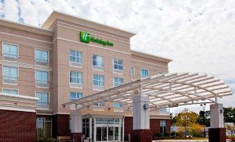 a holiday inn hotel with its logo and sign , under a clear blue sky with clouds at Holiday Inn Statesboro-University Area
