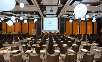 a large conference room with rows of chairs arranged in a semicircle , and a projector screen on the wall at Domina Zagarella Sicily
