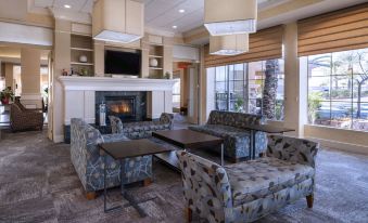 a spacious living room with multiple couches and chairs arranged in front of a fireplace at Hilton Garden Inn Las Vegas Strip South