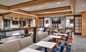 a modern restaurant with various dining tables and chairs , as well as a tv mounted on the wall at Hyatt House Provo/Pleasant Grove