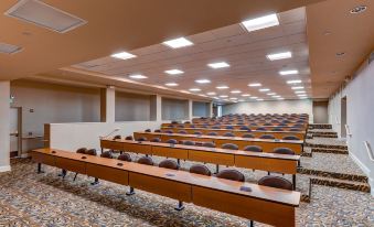 a large conference room with rows of wooden desks and chairs arranged in a semicircle at The Chateau Resort