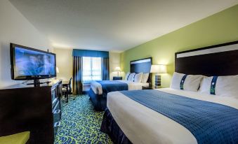 a modern hotel room with green walls , blue and white bedding , and a tv , desk , and window at Holiday Inn Richmond