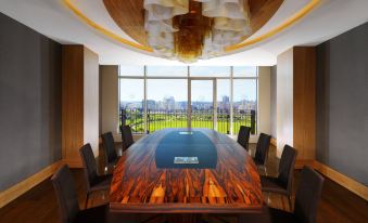 a conference room with a wooden table , chairs , and a view of a city through the window at Sheraton Grand Adana