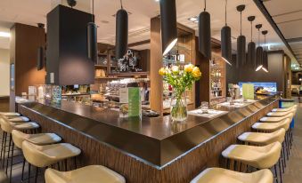 a modern restaurant with a bar counter and several chairs , as well as a dining area at Novotel Lugano Paradiso