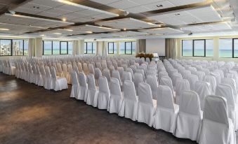 a large conference room with rows of chairs arranged in a symmetrical fashion , ready for an event at Grand Mercure Recife Boa Viagem