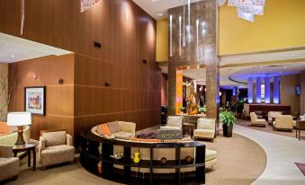 a modern hotel lobby with wooden paneling , comfortable seating arrangements , and a large chandelier hanging from the ceiling at Sonesta Milwaukee West Wauwatosa