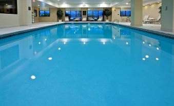 an indoor swimming pool with a blue water surface , surrounded by windows and overlooking the ocean at Holiday Inn Wilmington