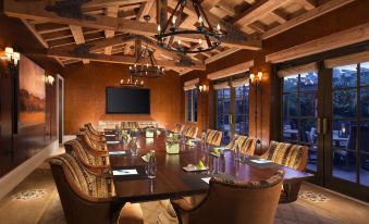 a conference room with a long wooden table , multiple chairs , and a tv mounted on the wall at Rancho Valencia Resort and Spa